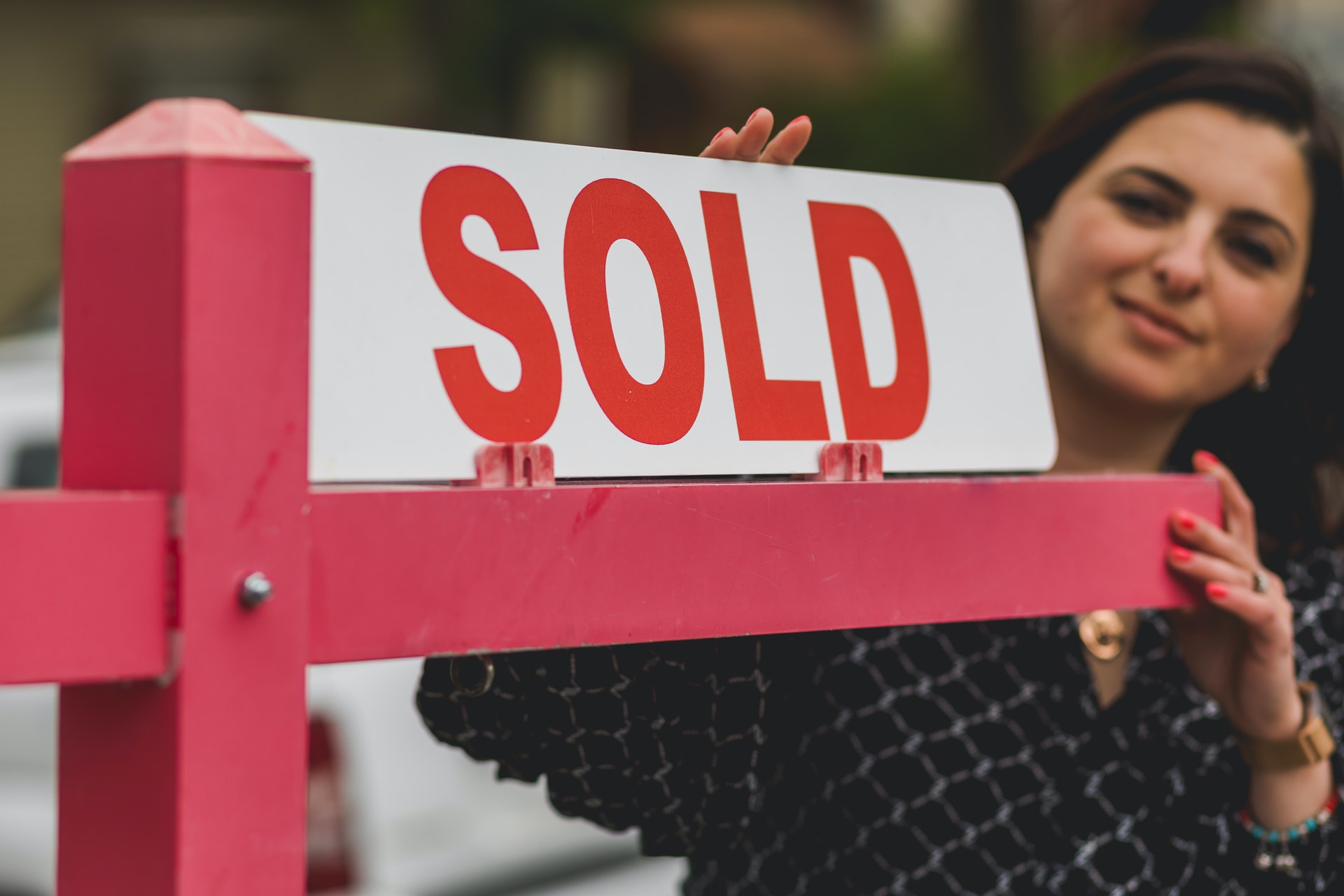 woman holding a sold sign